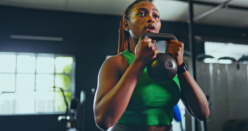 Diverse group of people engaging in various fitness activities including strength training, cardio exercises, and flexibility work in a modern gym environment